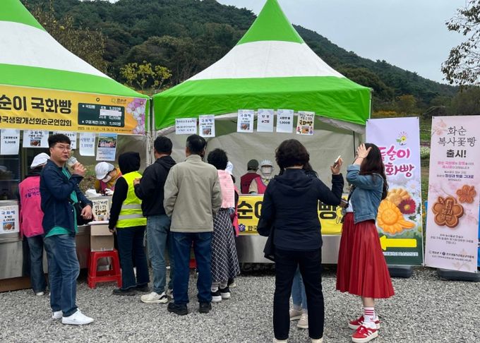 2025 화순고인돌가을꽃축제 현장에서 ‘복사꽃빵’을 홍보·판매 중인 한국생활개선화순군연합회 회원들 모습.