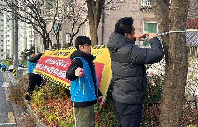서경대학교 학생들이 무단투기 금지 현수막을 달고 있다.
