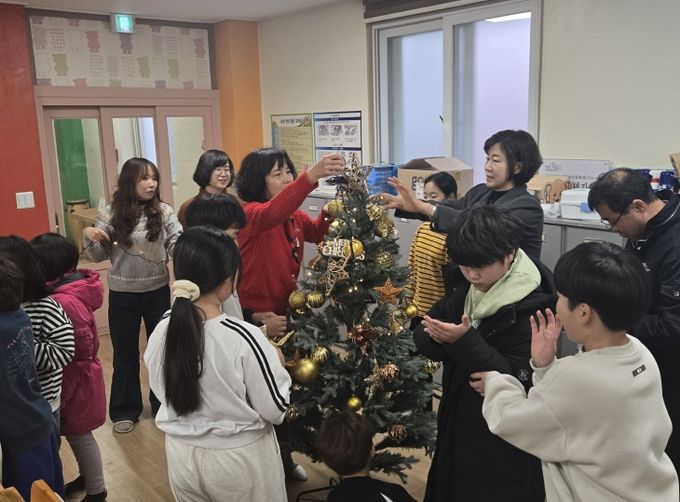 금산다락원 직원들이 사랑호크마지역아동센터 아동들과 크리스마스트리를 만들고 있다.