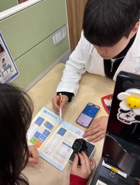 모바일 헬스케어사업 참여자가 모바일 앱(채움건강)과 활동량계(스마트밴드)에 대한 설명을 듣고 있다.