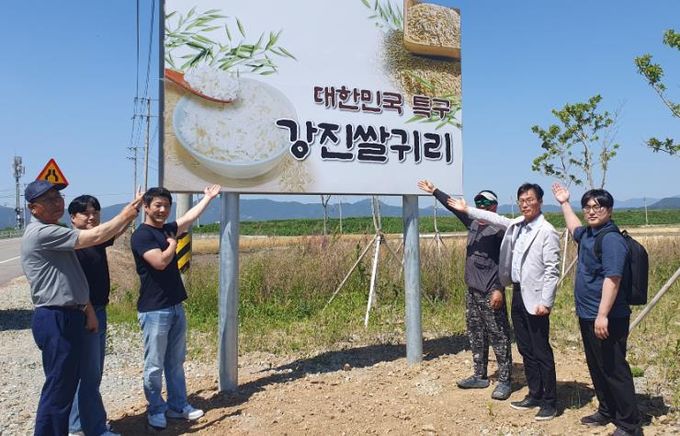 강진군 쌀귀리연구회 임원과 유통 관계자들이 쌀귀리 홍보 간판앞에서 기념촬영을 하고 있다.