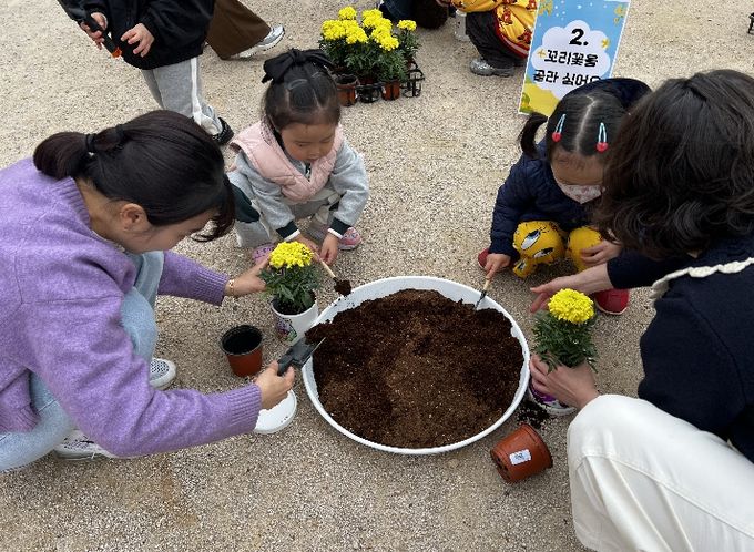 강동유치원 3세반 유아들과 학부모들이 14일 '보호자 참여 수업'의 하나로 꼬리꽃을 심고 있다.