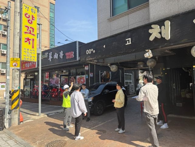 정명조 건축과장과 관계자들이 도로변 상가 간판의 안전 상태를 확인하며 현장점검을 하고 있다.